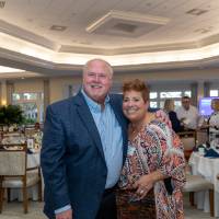 Beth Rinvelt and gentleman guest standing together and smiling at camera